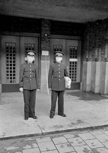 853244 Afbeelding van twee zaalwachters van de P.T.T., voor de ingang van het Hoofdpostkantoor (Neude 11) te Utrecht.